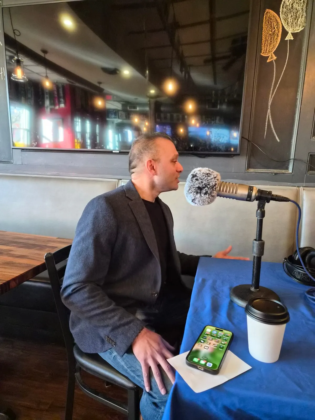 Romel D'Munda speaking into a studio microphone during a New Jersey 101.5 radio appearance